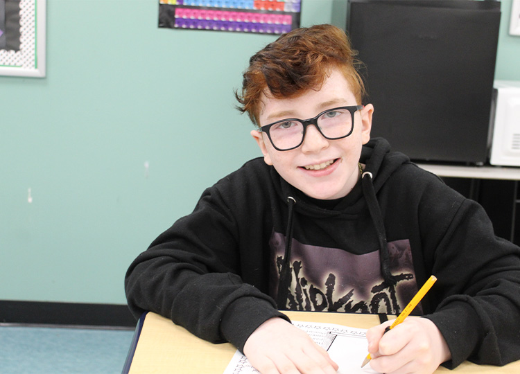 boy smiling at desk mobile image